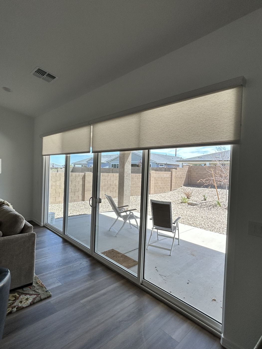 Light-filtering roller shades with cassettes raised above a wall of sliding glass doors in a Prescott-area home